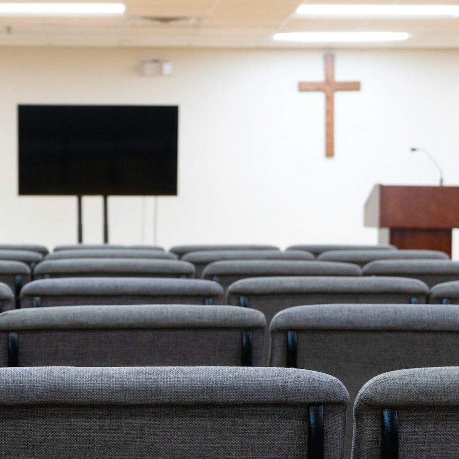 Chemin de foi – accompagnement chrétien Intérieur d’une église avec sièges alignés face à une croix et un pupitre